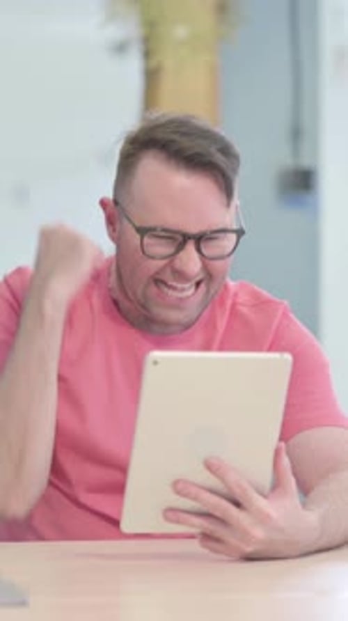 Excited Man Celebrates Success Using Tablet Device