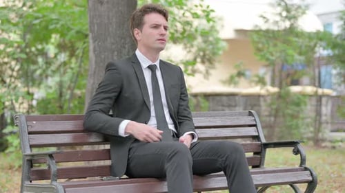 Man in Suit with Back Pain on Park Bench