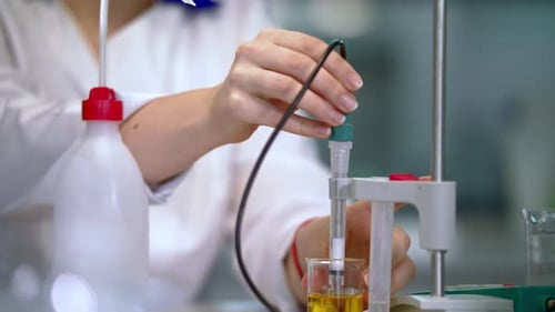 Woman Scientist with Lab Equipment Measuring Yellow Liquid