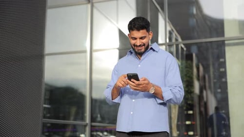 Happy Man Surfing Internet on Smartphone While Walking on Street