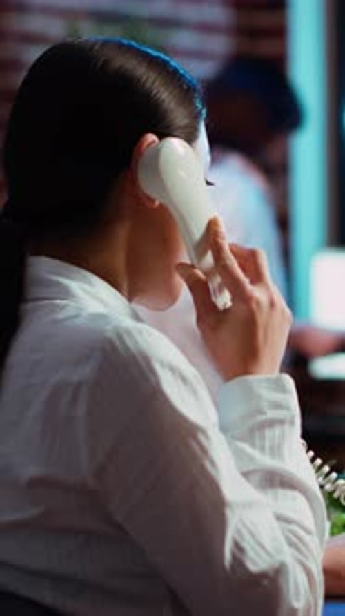 Vertical Video Employee Taking Landline Telephone Call While Working with Financial Graphs
