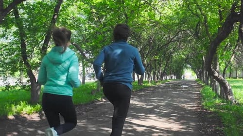 Sportive young people running. Couple run in the park during the day
