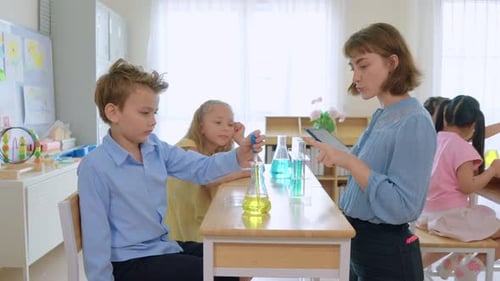 Adorable student learn with teacher in classroom at elementary school.