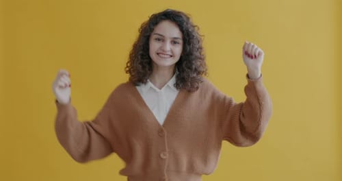 Happy Woman Dances Against Yellow Background