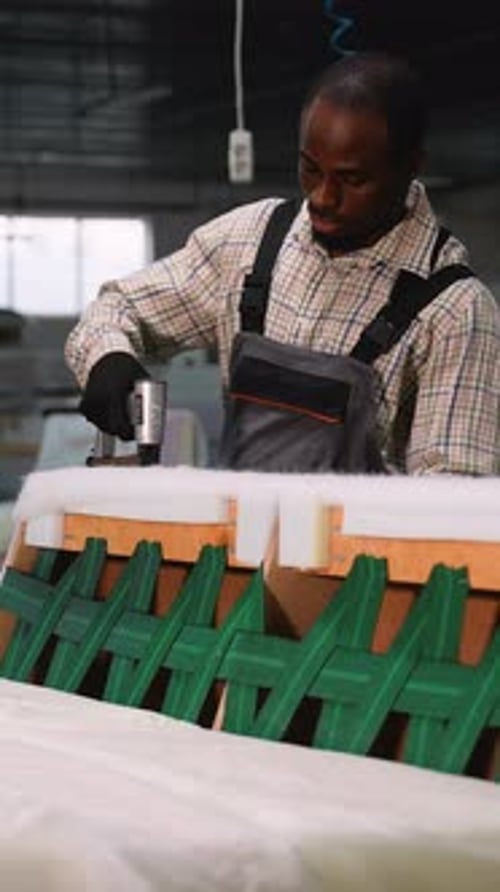 Man Using Staple Gun on Cushioned Item
