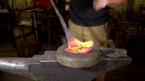 Blacksmith Shaping Red-Hot Metal on Anvil with Hammer