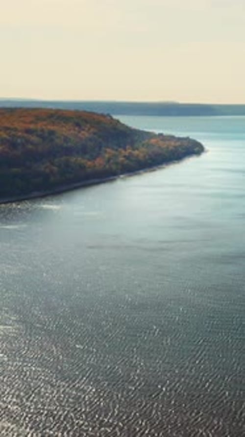Litoral iluminado pelo sol de um penhasco arborizado de Door County que se estende até a baía azul — vista aérea