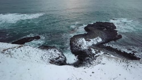 The aerial view moves over the cliff to expose Icelandic coast line