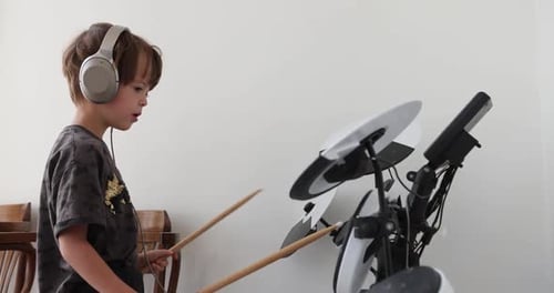 Boy Plays Electronic Drum Set With Headphones