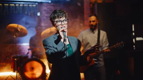 Female Singer Performing on Dark Stage with Band