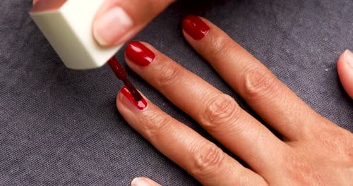 Applying Dark Red Nail Polish to Fingernails