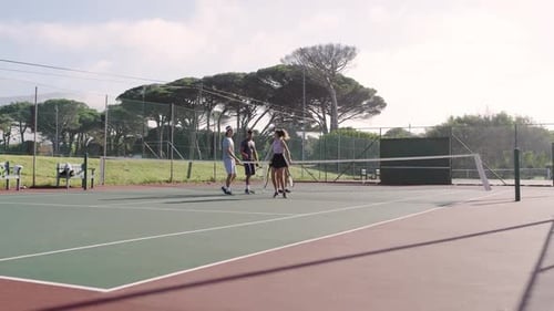 Quittant la ligne de fond, divers amis se serrent la main devant un filet de tennis, discutent et repartent après le match