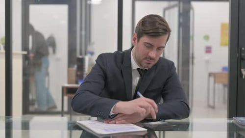 Man Calculating at Desk in Modern Office