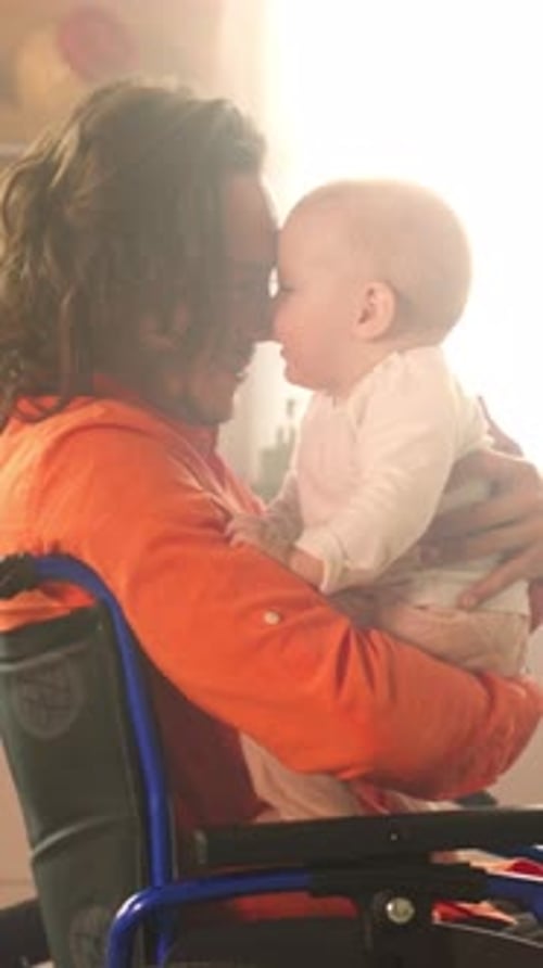 Father in Wheelchair Holding Baby in Bright Room