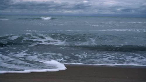 Stormy sea waves crashing on a tropical beach in a dark weather ocean landscape