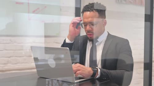 Stressed Businessman Typing on Laptop in Bright Office