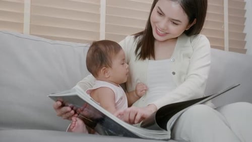 Smiling Woman Reading with Baby on Couch