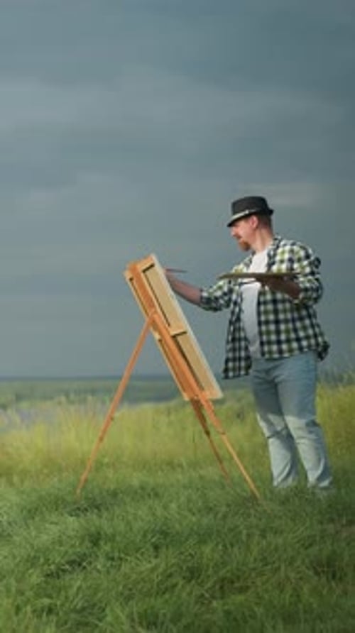 Artist Painting Woman in White Dress and Hat By Lakeside Field