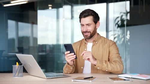 Man using smartphone in office, receives good news