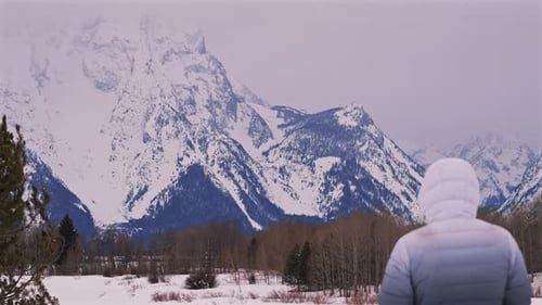Person Observes Snowy Mountains in Winter Landscape