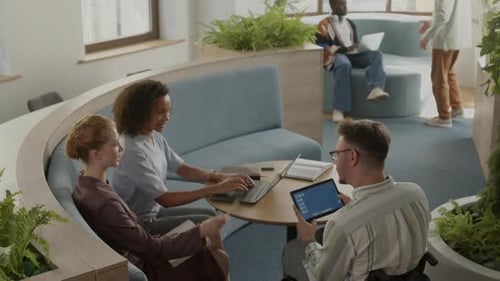 Man in Wheelchair Speaking with Female Colleagues in Coworking Office