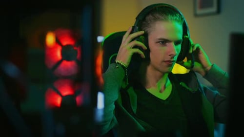 Young Man Putting on Headphones in Gaming Room