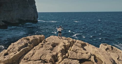 Stunning Aerial Shot of Adventurous Girl Climbing Rocks By the Ocean Shore