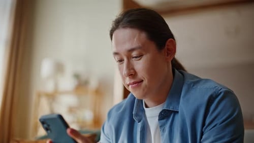 Man Using Smartphone Device in Bright Home Setting