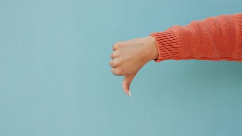 Thumbs down, dislike hand emoji or vote sign mockup on studio or blue wall background