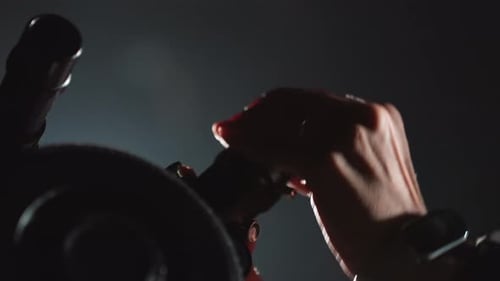 Woman Exercising on Stationary Bike in Dark Gym