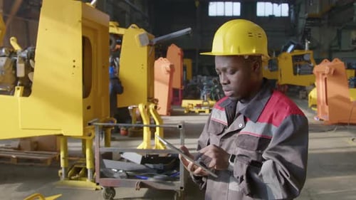 Factory Supervisor Using Tablet Standing near Engine Mounting Frames