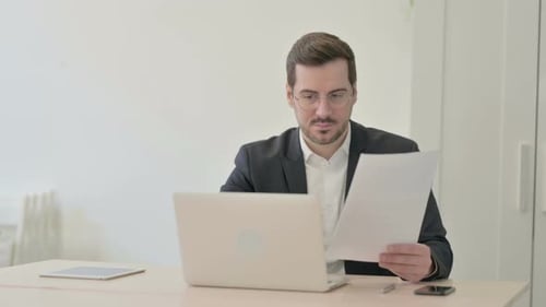 Smiling Man Celebrating Success in Modern Workplace