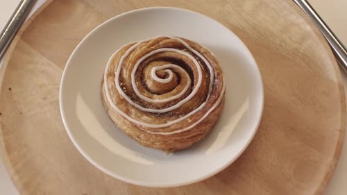 Rotierende Zimtschnecke auf weißem Teller