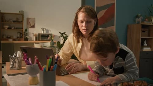 Woman Working Remotely and Watching Little Son Drawing with Pink Marker