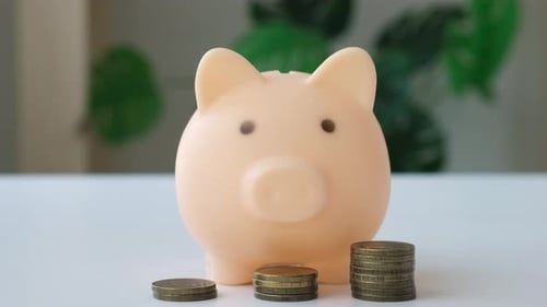 Female Hand Putting Coins Into Piggy Bank Investing in Future