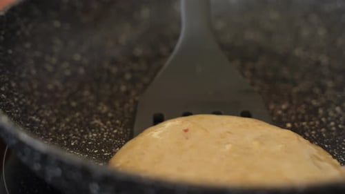 Kreppkuchen auf einer Bratpfanne mit Spatel in Zeitlupe umdrehen, Nahaufnahme