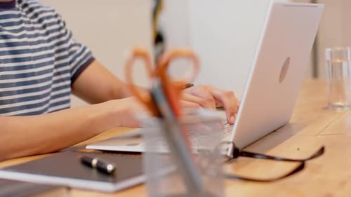 Young Adult Typing on Laptop at Desk