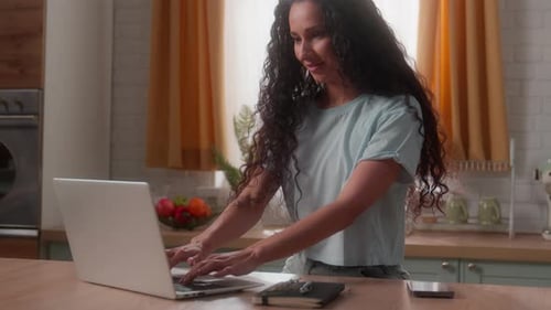 Woman Typing on Laptop Computer in Bright Kitchen