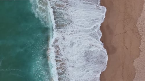 Stunning Aerial View of Beautiful Beach Waves Lapping Against the Sandy Shoreline