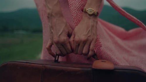 Woman Holds Suitcase in Rural Field