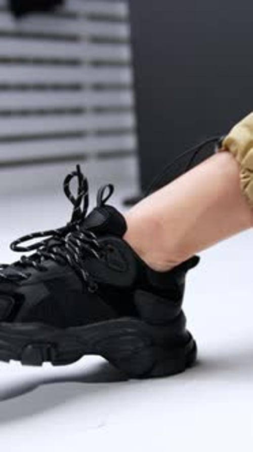 Woman Tying Laces on Trendy Black Sneakers