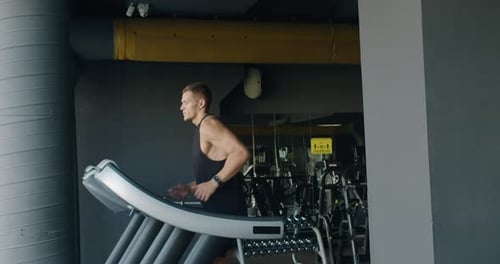 Young Man Running On Treadmill In Modern Gym Setting