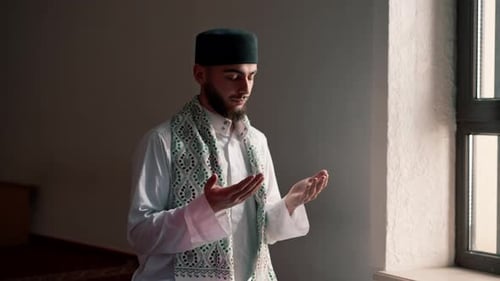 Close-up shot of a Muslim man's hands praying on his knees during Ramadan in Islamic temple