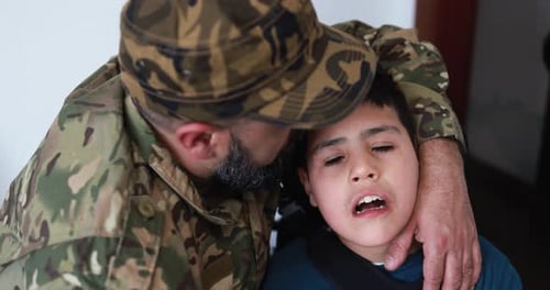 Man in Military Uniform Hugging Child Indoors