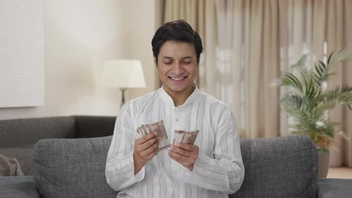 Man Counting Cash Money Indoors on Couch