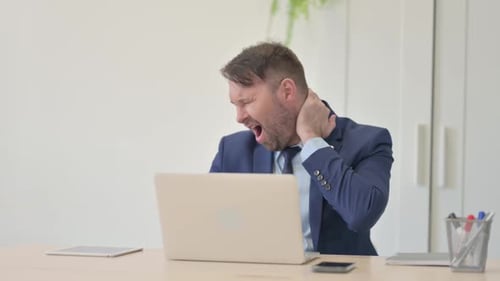 Man at Desk Has Neck Pain While Working