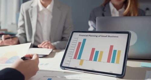 Financial Business Meeting with Charts and Tablet