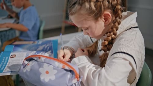 Little Kid Writing Exercises in Notebook in Elementary School Class Closeup
