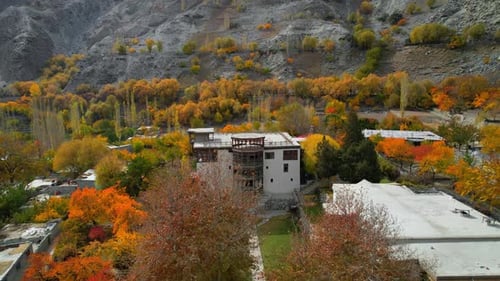 Vue aérienne du palais de Khaplu au milieu d'arbres automnaux vibrants. Reculer, tirer vers le haut