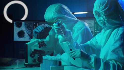Scientists in Protection Suits and Masks Working in Research Lab Using Laboratory Equipment